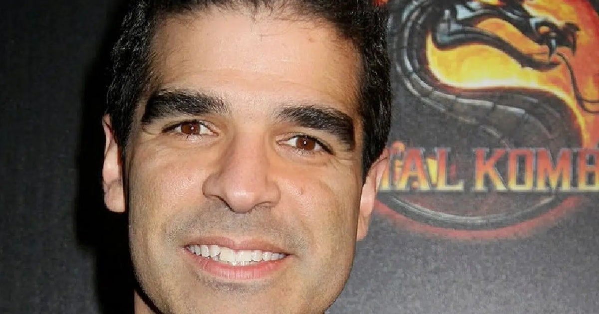 Mortal-Kombat-Miterfinder Ed Boon vor einem Mortal-Kombat-Motiv