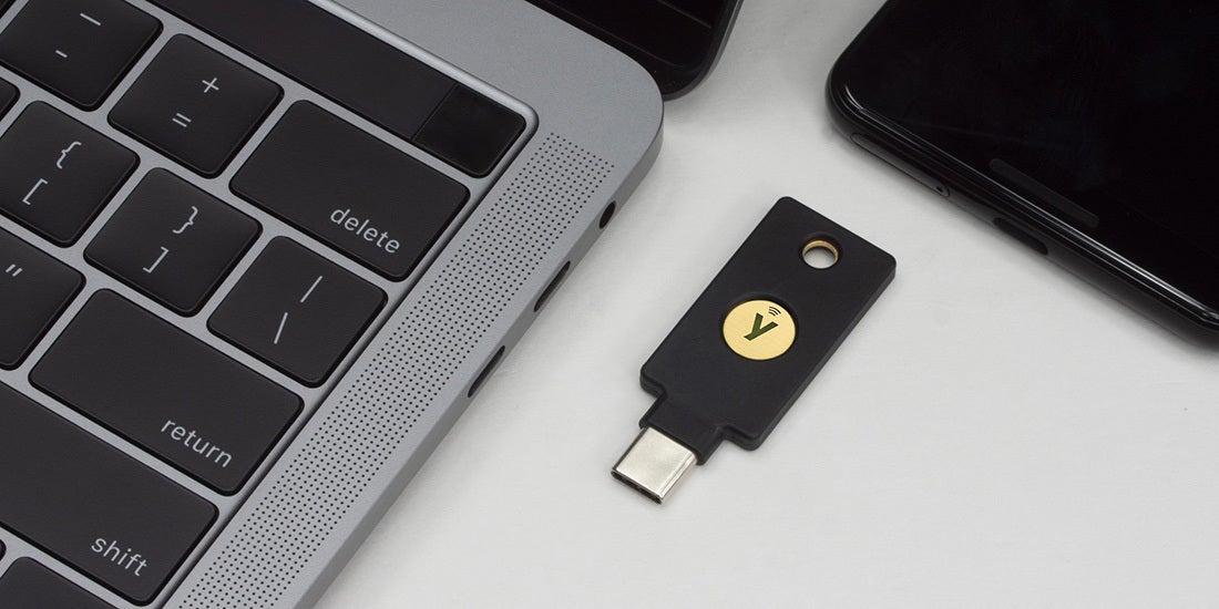 YubiKey mit Firmware 5.7 neben Laptop und Smartphone - Bild: Yubico