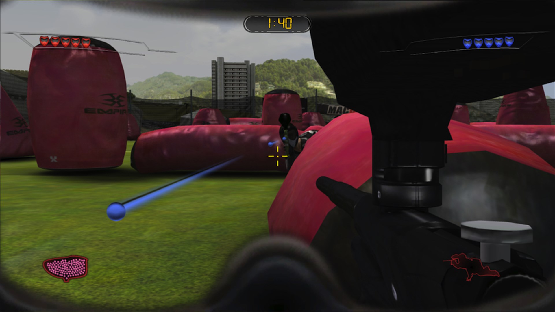 Spielfeld aus Greg Hastings Paintball 2 mit roten Hindernissen und einem Paintball-Markierer im Vordergrund