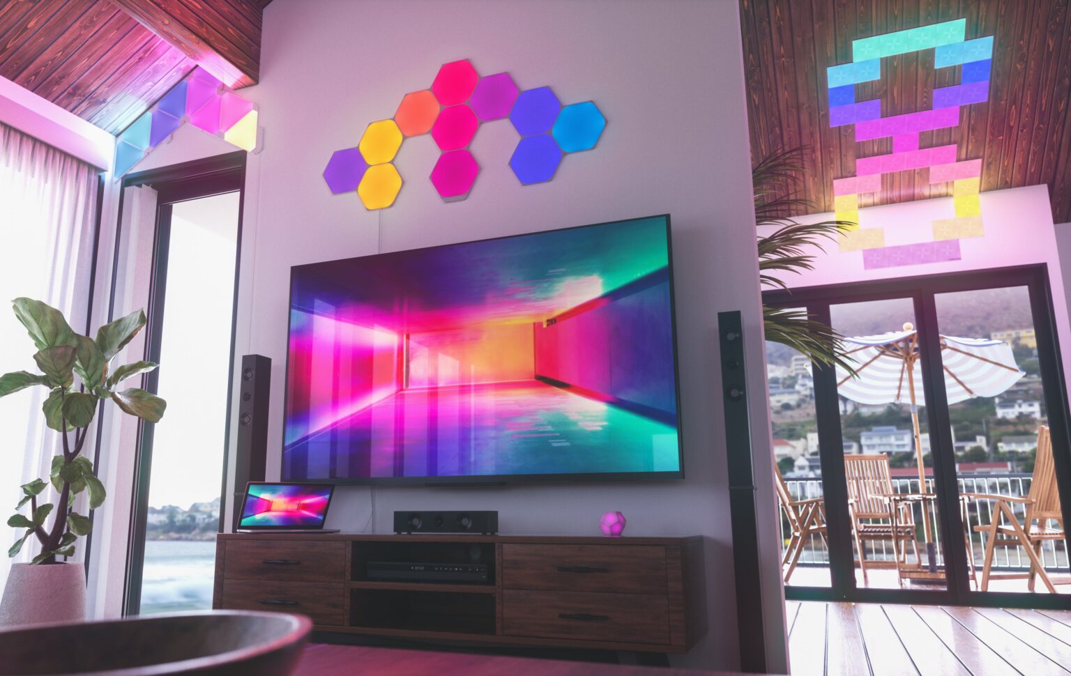 Farbig leuchtende Nanoleaf Shapes rund um einen Fernseher und an mehreren Wänden - Bild: Nanoleaf