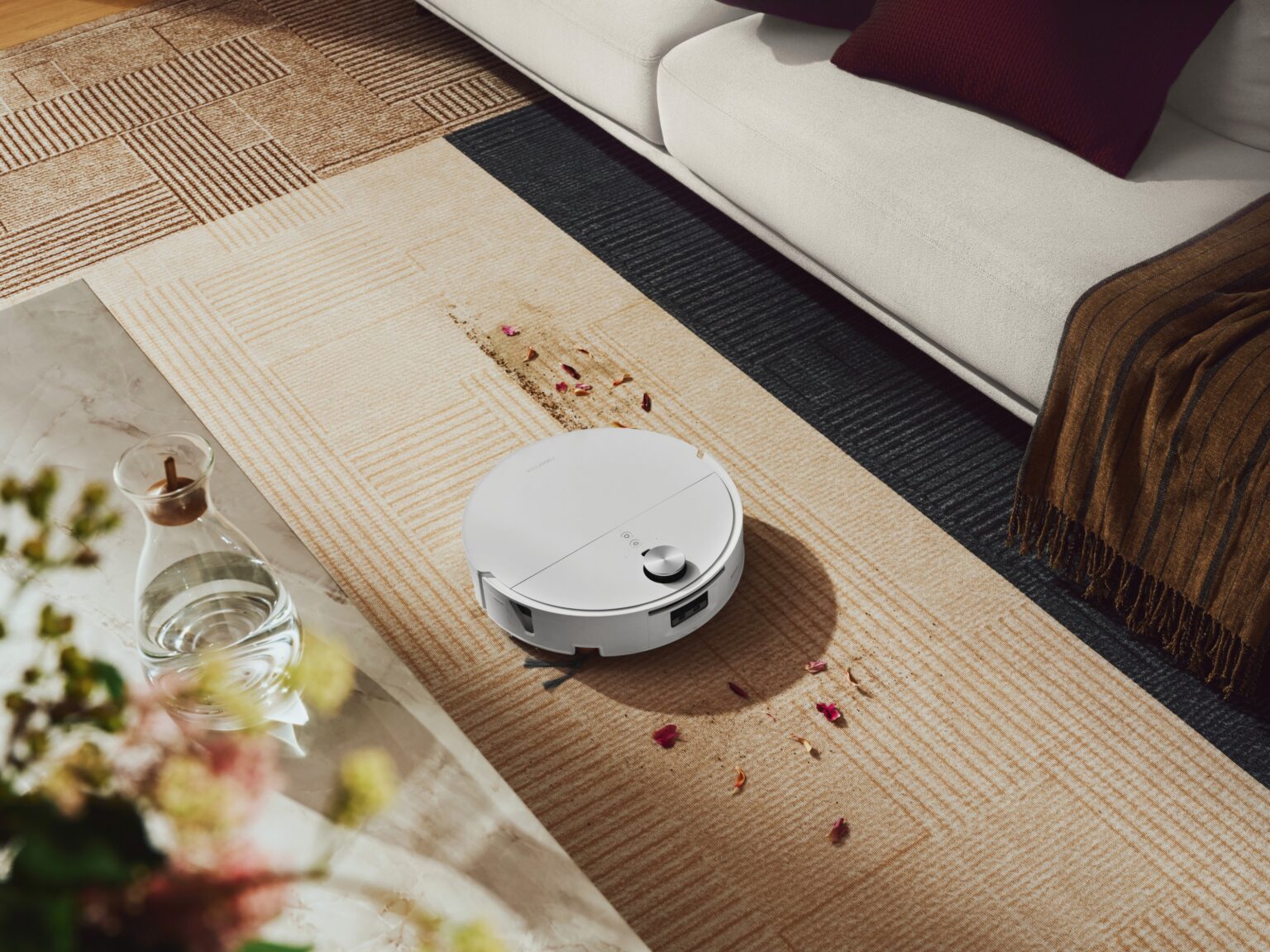 Weißer Roborock Saros 20 Flow Complete fährt über einen hellen Teppich im Wohnzimmer