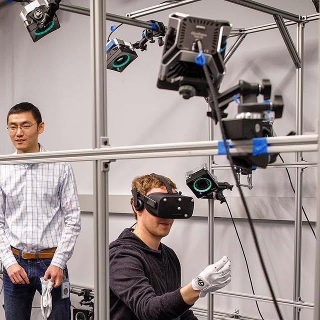 Mark Zuckerberg mit VR-Headset und weißem Forschungshandschuh in einem Kamerarahmen, Originalfoto vom Februar 2017 - Bild: Mark Zuckerberg / Oculus