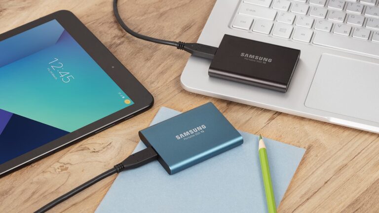 Blaue und schwarze Samsung Portable SSD T5 neben Tablet und Notebook, offizielles Pressebild von 2017 - Bild: Samsung