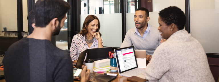Vier Personen arbeiten mit Microsoft Teams an einem Konferenztisch - Bild: Microsoft
